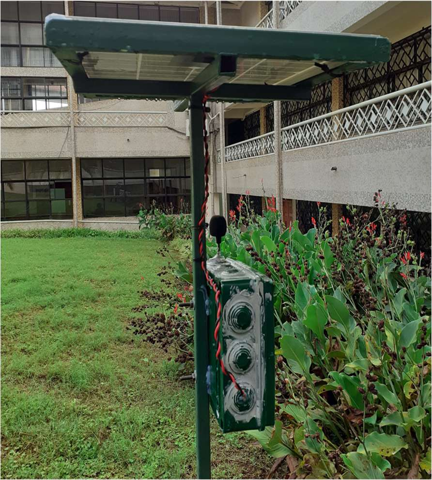 A DSAIL camera trap mounted on a post in a grassy field