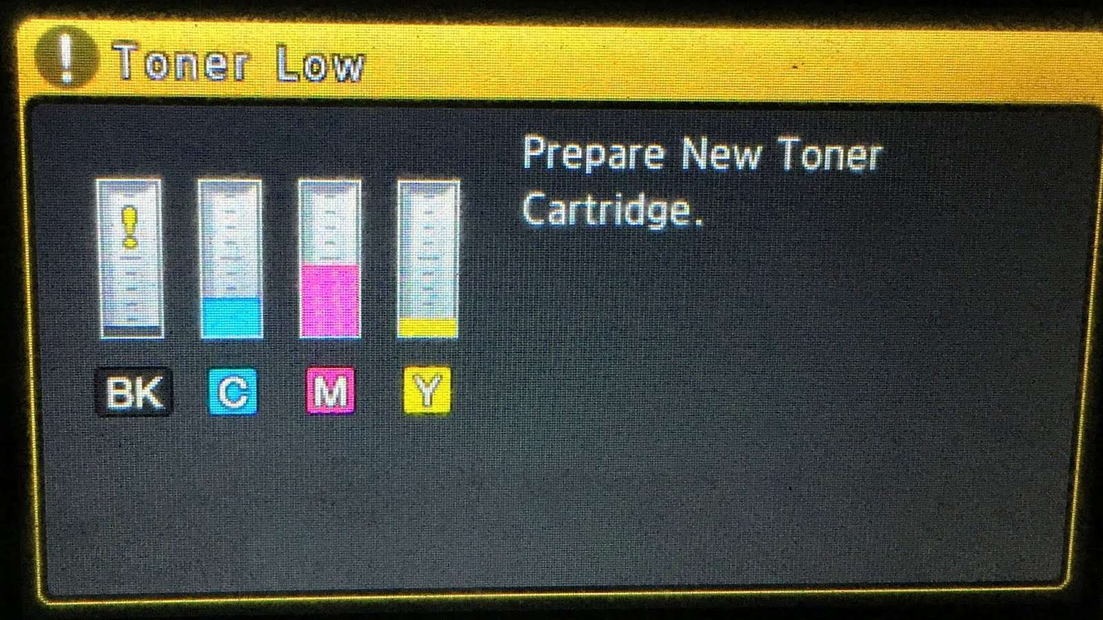 A printer's diagnostic display showing a 'Toner Low' warning with a prompt to prepare a new toner cartridge